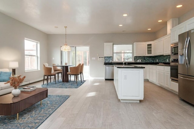 kitchen featuring appliances with stainless steel finishes, light wood-type flooring, sink, decorative light fixtures, and white cabinetry