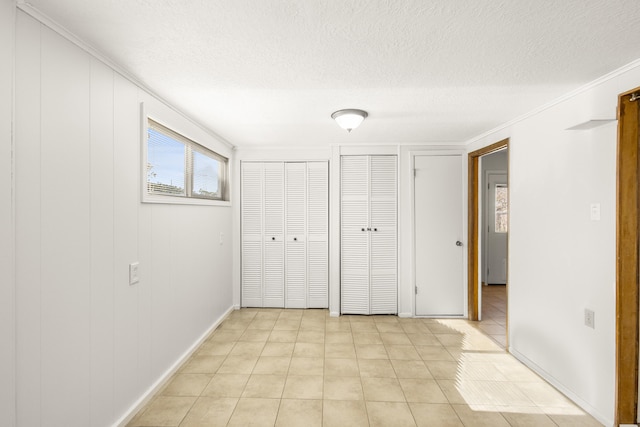 unfurnished bedroom featuring multiple closets, light tile patterned floors, and a textured ceiling