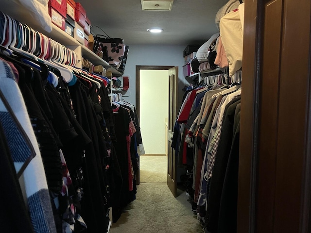 walk in closet with light carpet