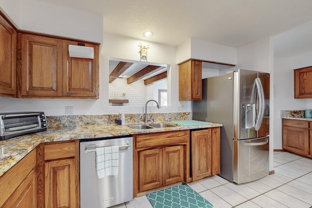 kitchen with light stone countertops, light tile patterned floors, appliances with stainless steel finishes, beamed ceiling, and sink