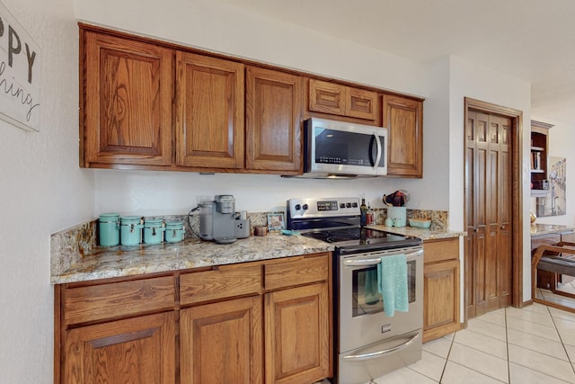 kitchen featuring appliances with stainless steel finishes, light stone countertops, and light tile patterned floors