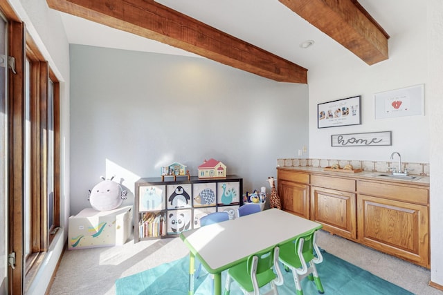 carpeted dining room with sink and vaulted ceiling with beams