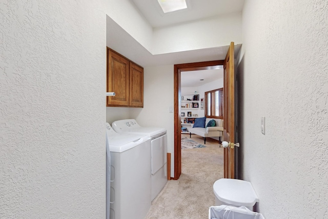 clothes washing area with light colored carpet, cabinets, and separate washer and dryer