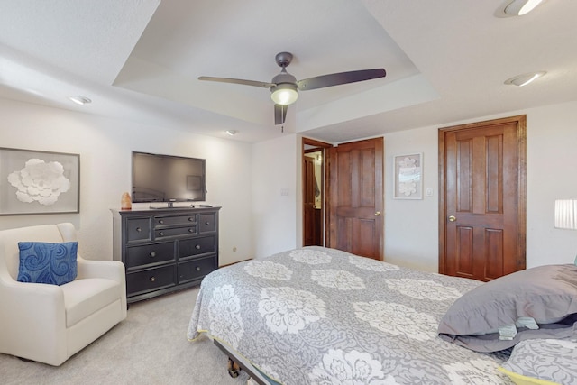 carpeted bedroom featuring a raised ceiling and ceiling fan