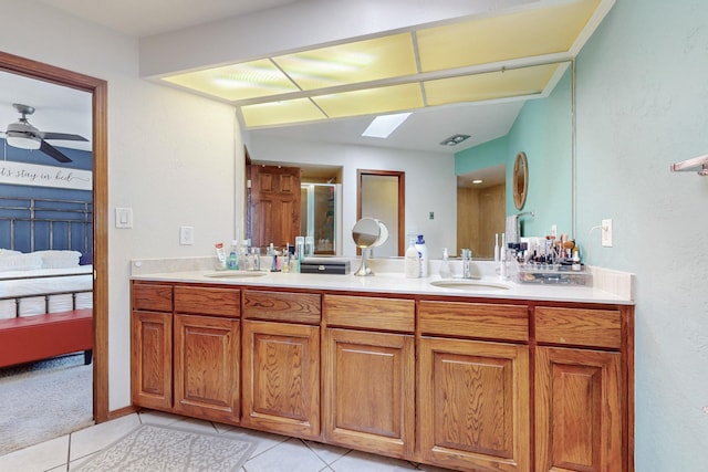 bathroom with tile patterned flooring, ceiling fan, a skylight, an enclosed shower, and vanity