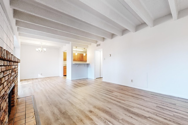 unfurnished living room with beam ceiling, light wood-type flooring, a fireplace, and a chandelier