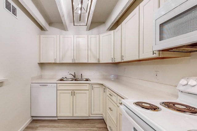 kitchen featuring beamed ceiling, white appliances, light hardwood / wood-style floors, and sink