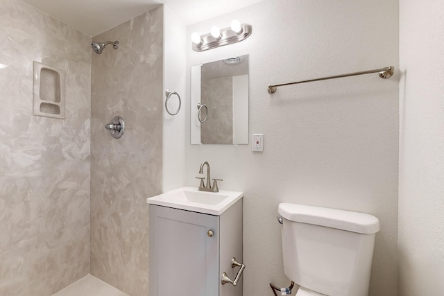 bathroom with tiled shower, vanity, and toilet