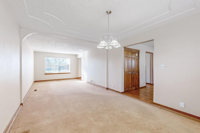 unfurnished room with a notable chandelier, carpet floors, and a textured ceiling