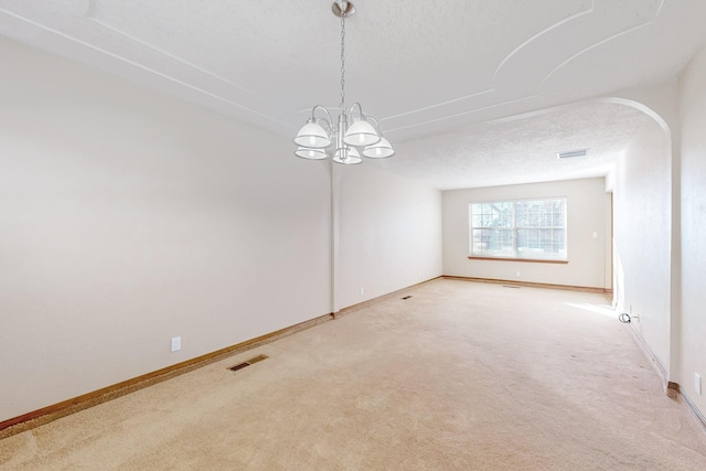 spare room with carpet floors, a chandelier, and a textured ceiling