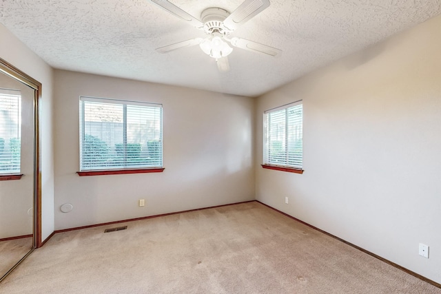 carpeted spare room with a textured ceiling and ceiling fan