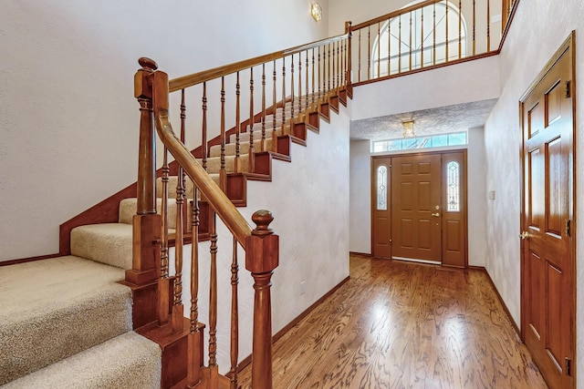 entrance foyer featuring a towering ceiling and wood-type flooring