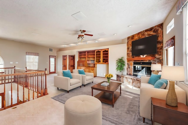 carpeted living room with rail lighting, ceiling fan, a textured ceiling, and a fireplace