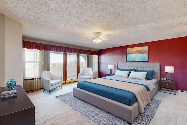 bedroom with ceiling fan, access to outside, a textured ceiling, and carpet