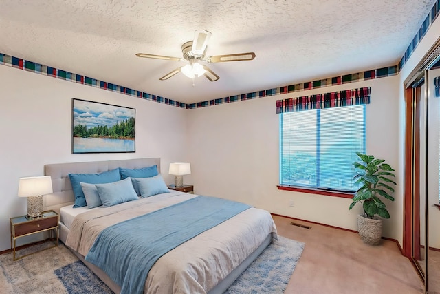 carpeted bedroom with ceiling fan and a textured ceiling