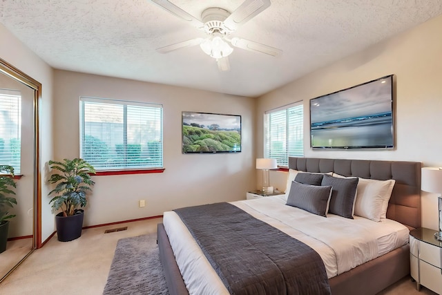 carpeted bedroom with ceiling fan and a textured ceiling