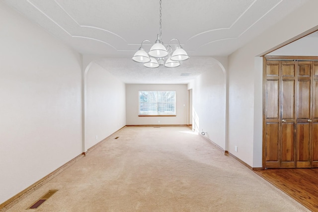 carpeted empty room featuring a notable chandelier