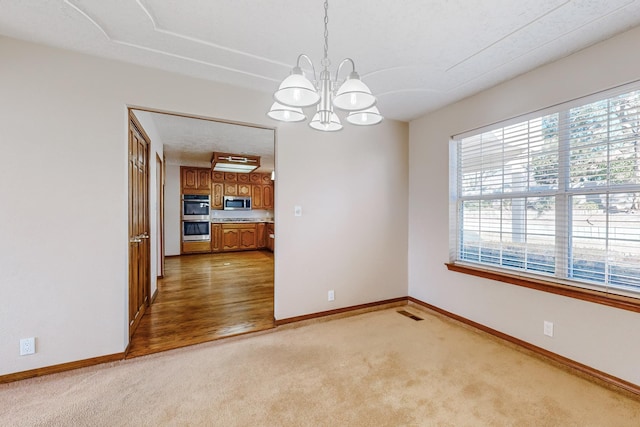 carpeted empty room featuring an inviting chandelier