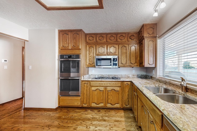 kitchen featuring hardwood / wood-style flooring, stainless steel appliances, sink, and light stone counters