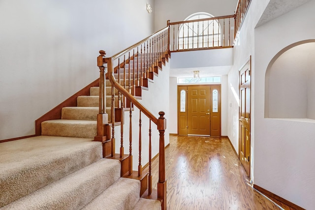 entryway featuring hardwood / wood-style flooring and a towering ceiling