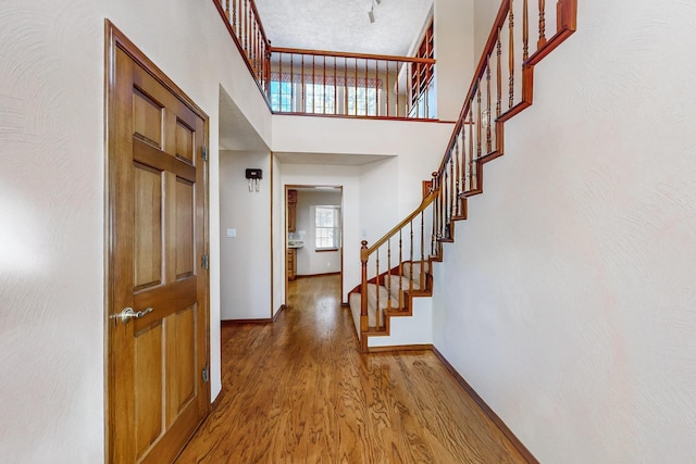 entryway featuring hardwood / wood-style flooring, a towering ceiling, and a textured ceiling