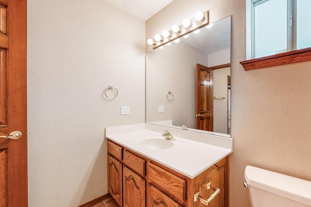 bathroom with vanity, toilet, and a textured ceiling