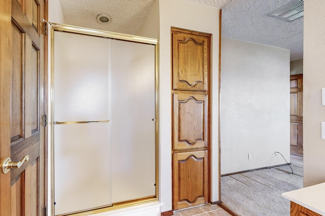 bathroom featuring vanity, a shower with door, and a textured ceiling