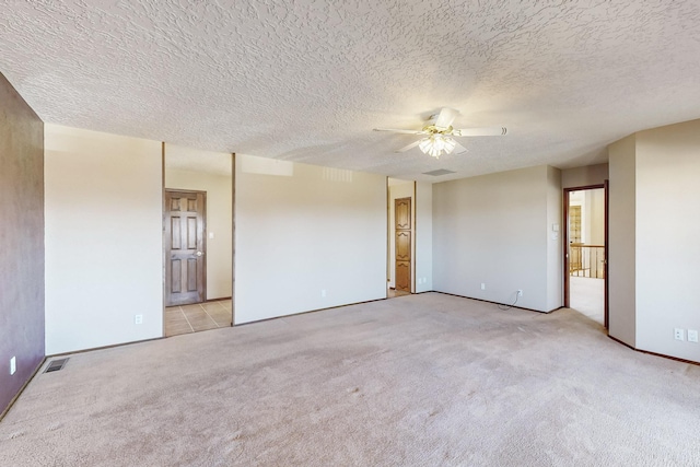 spare room with light colored carpet, a textured ceiling, and ceiling fan