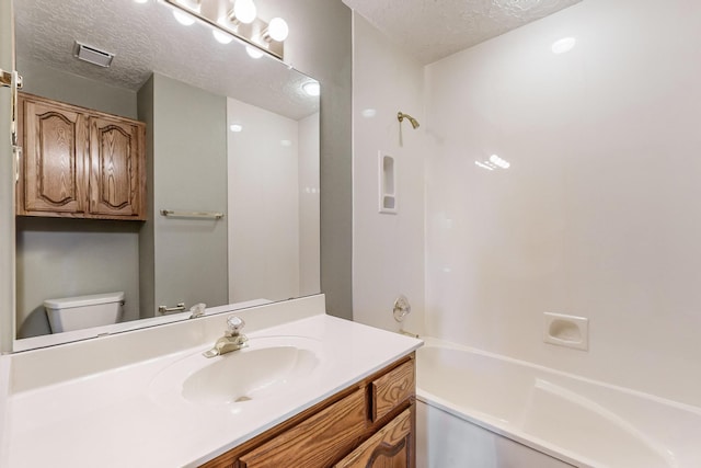 full bathroom featuring shower / washtub combination, vanity, a textured ceiling, and toilet