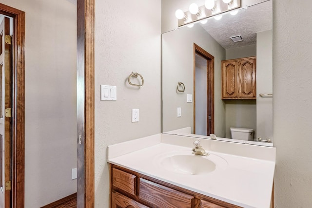 bathroom with vanity, a textured ceiling, and toilet