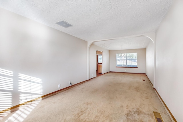 empty room with light carpet and a textured ceiling