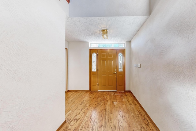 doorway to outside featuring light hardwood / wood-style flooring and a textured ceiling