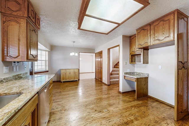 kitchen featuring a textured ceiling, dishwasher, pendant lighting, light stone countertops, and light hardwood / wood-style floors