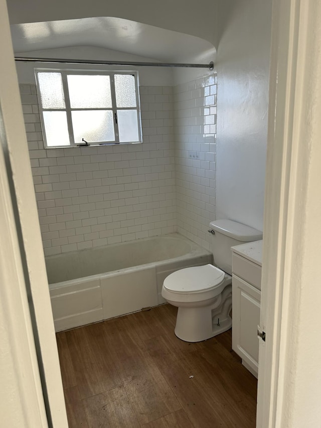 full bathroom featuring vanity, vaulted ceiling, tiled shower / bath combo, toilet, and wood-type flooring