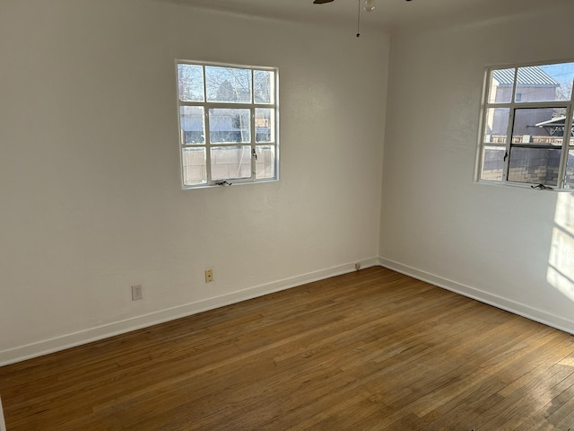 empty room with dark hardwood / wood-style floors, plenty of natural light, and ceiling fan