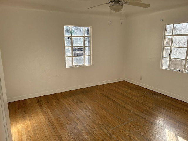 empty room featuring a wealth of natural light, hardwood / wood-style floors, and ceiling fan