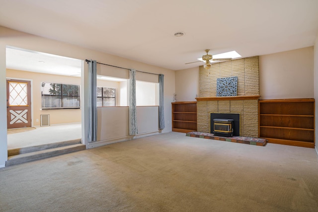 unfurnished living room with a wood stove, a wealth of natural light, and carpet