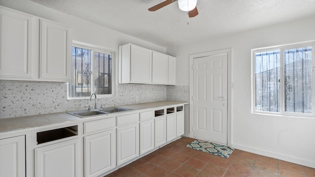 kitchen featuring white cabinets, backsplash, ceiling fan, and sink