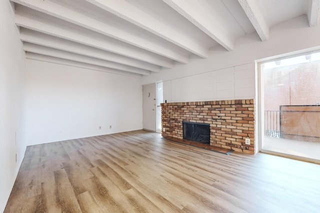 unfurnished living room featuring a fireplace, light hardwood / wood-style flooring, and beamed ceiling