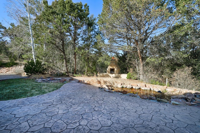 exterior space featuring an outdoor stone fireplace and a patio area