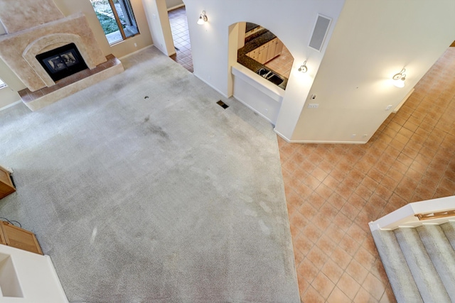 unfurnished living room featuring a tile fireplace and light colored carpet