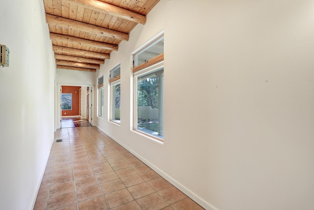 corridor featuring beamed ceiling, wooden ceiling, and light tile patterned flooring