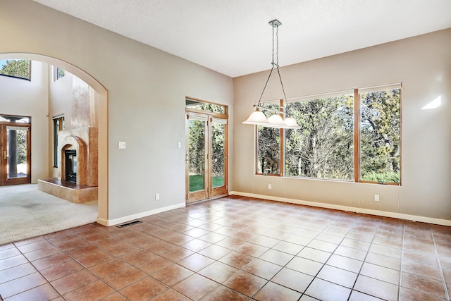 tiled empty room with a textured ceiling and a tiled fireplace