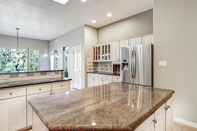 kitchen with a center island, dark stone counters, and stainless steel refrigerator with ice dispenser