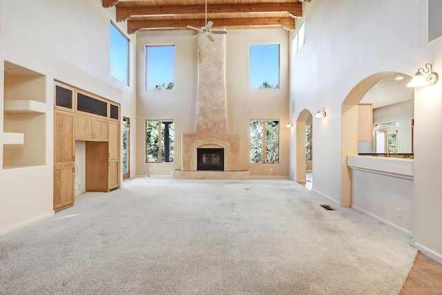 unfurnished living room featuring a towering ceiling, a high end fireplace, and a healthy amount of sunlight