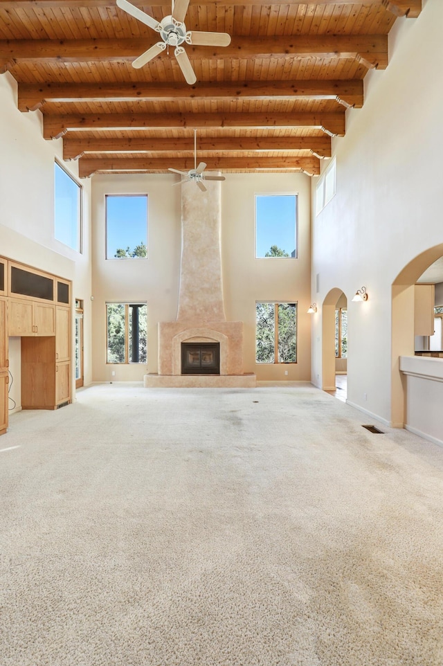 unfurnished living room featuring a fireplace, a towering ceiling, and wood ceiling