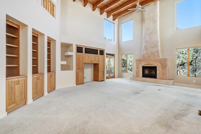 unfurnished living room featuring light colored carpet, built in features, a fireplace, and a high ceiling