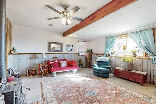 6284 State Highway 55, Mountainair, NM 87036 - living room featuring a wood stove, wood walls, healthy amount of natural light, a wainscoted wall, and a ceiling fan