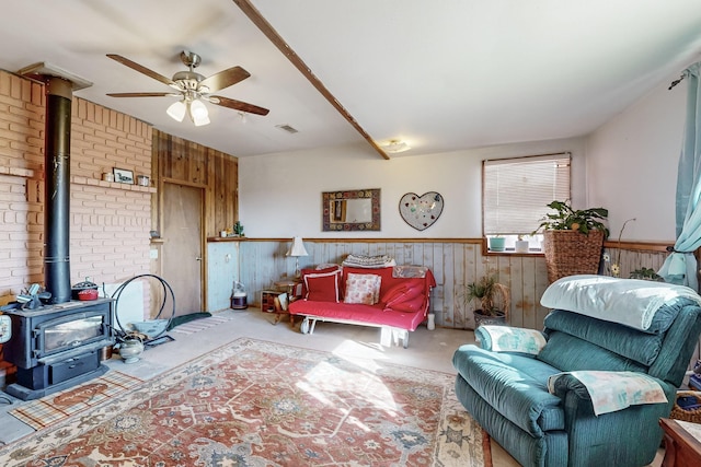 6284 State Highway 55, Mountainair, NM 87036 - living room with a wood stove, wood walls, ceiling fan, a wainscoted wall, and carpet
