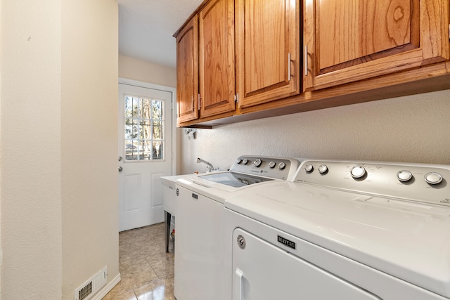 laundry room featuring cabinets, light tile patterned floors, and washing machine and dryer